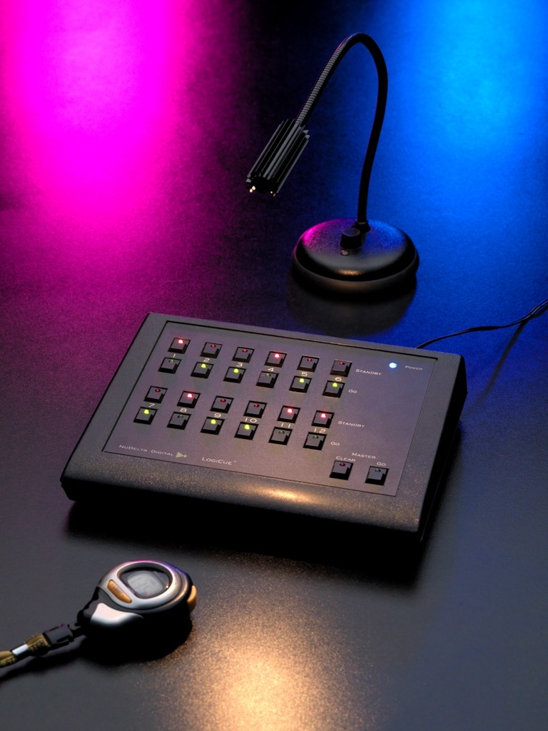 A picture of two LogiCue QL2 Digital Cue Lights, part of the LogiCue Digital Cue Light System. One cue light is illuminated red and the other is blue.